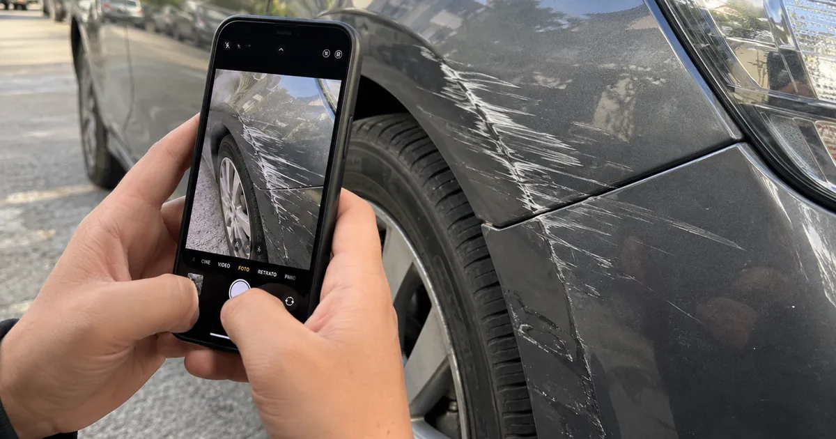 Persona sacando fotos con el celular al daño de su auto